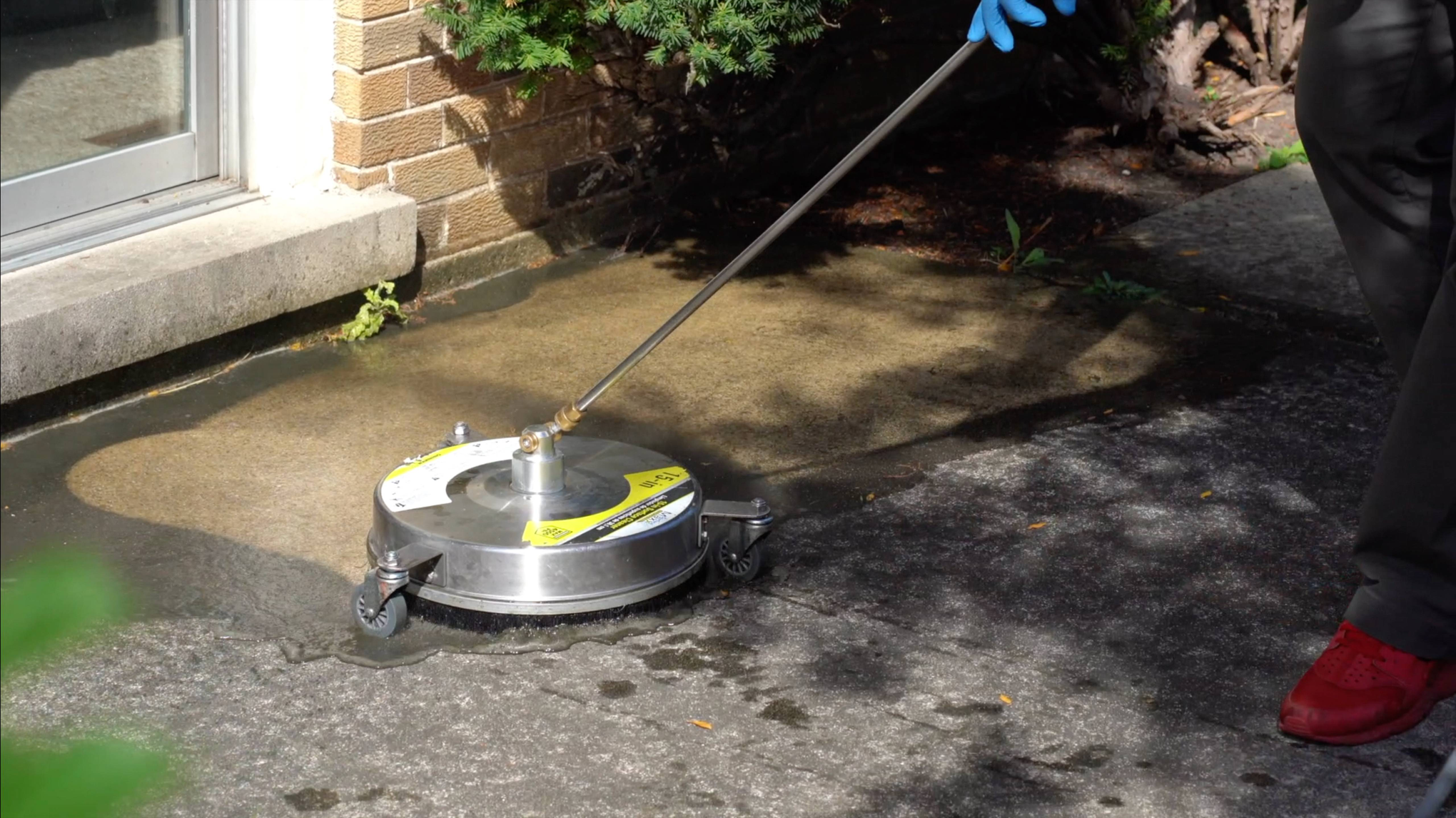 DAB Pressure Washing technician using a flat surface cleaner on a concrete driveway in Champaign County